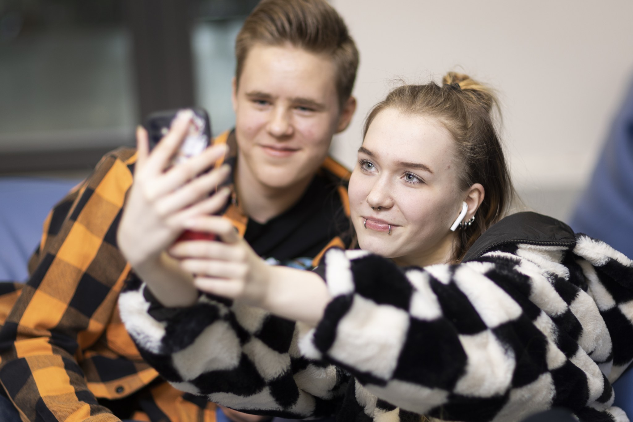 Kaksi nuorta poseeraa kännykän etukameraan katsoen.